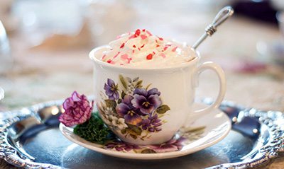 Hot drink topped with whipped cream in floral teacup