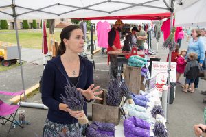 Vendor at farmers market tent arranges lavender and pillows