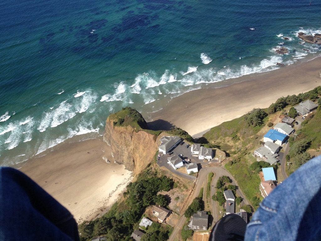 View through photographers feet looking down on the ocean and beach town
