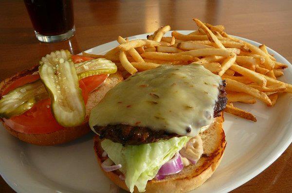 Open-faced cheeseburger with pickles, tomatoes, lettuce, onions and a side of fries