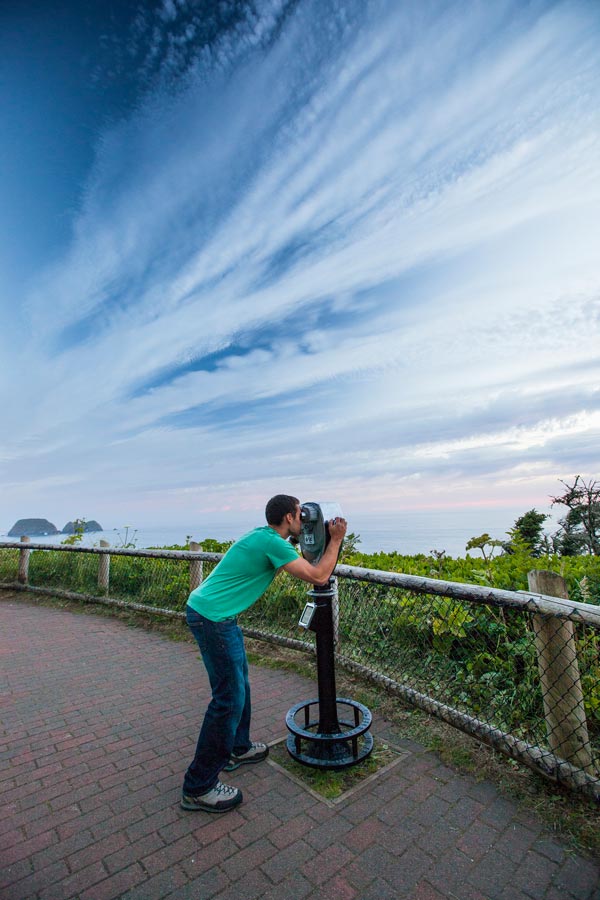 Man looks through coin-operated binoculars outside Cape Meares Lighthouse
