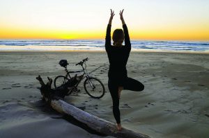 Person in tree pose on the beach at sunrise