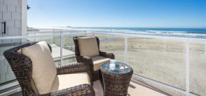 Balcony with two wicker chairs and a table, view of the beach