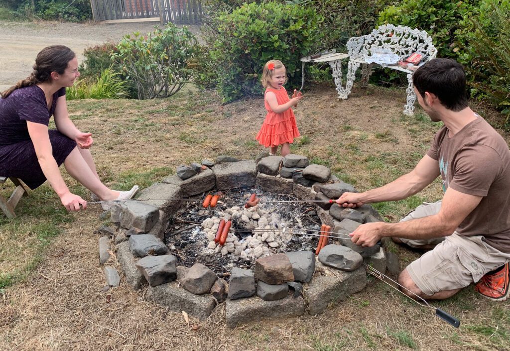 family fire cooking hotdogs daytime