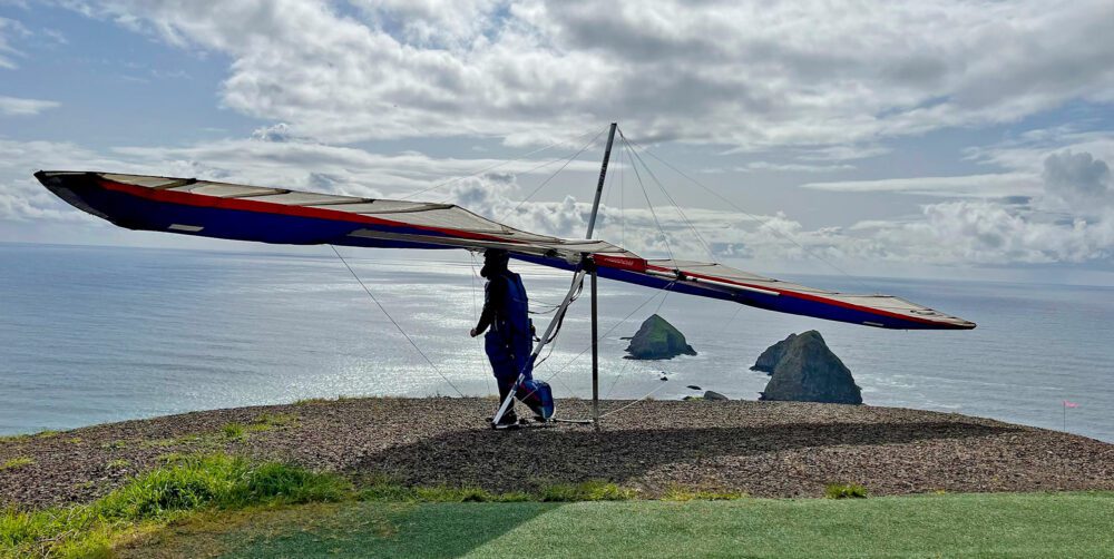hanglider cliff edge cloudy sky ocean view sea stacks
