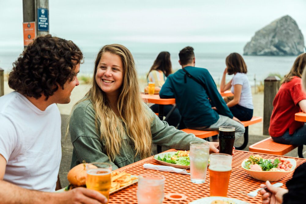 pelican brewing patio lunch tables people ocean sea stack
