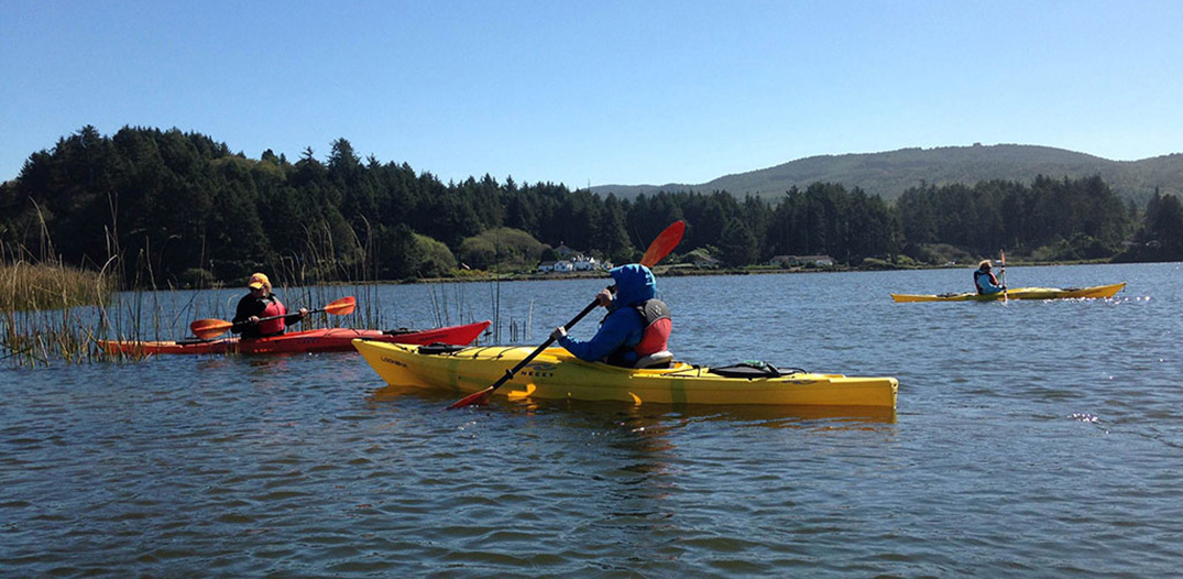 Three people in kayaks paddle in the lake