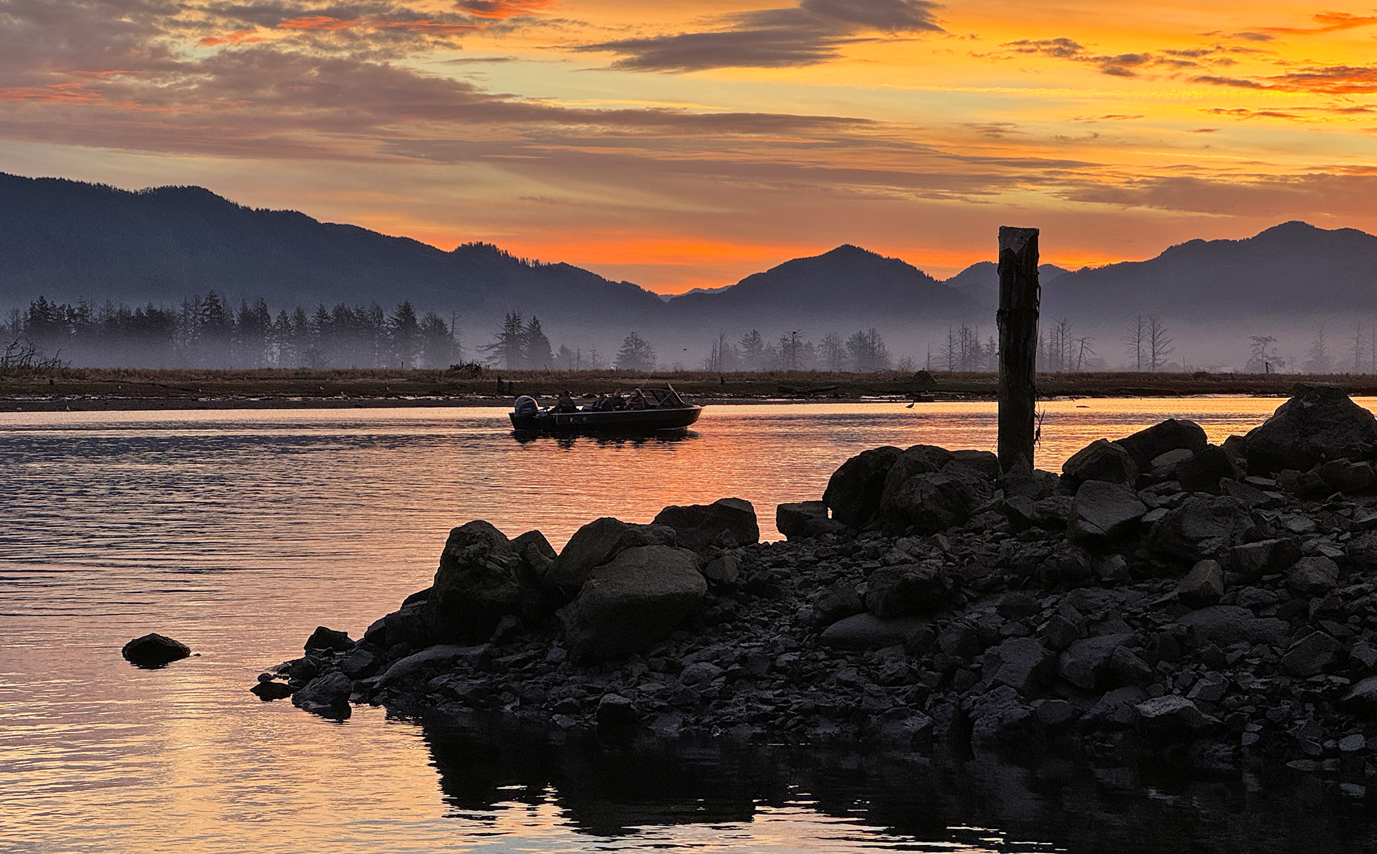 sunset fishing boat rocky shore mountains